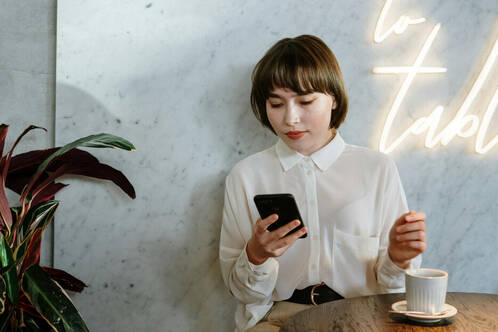 Frau im Café prüft ihr iPhone