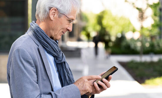 älterer Herr tippt auf seinem iPhone