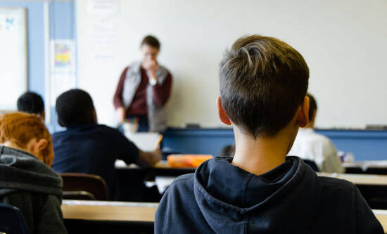 Schüler sitzt in Schulzimmer und schaut zur Lehrperson
