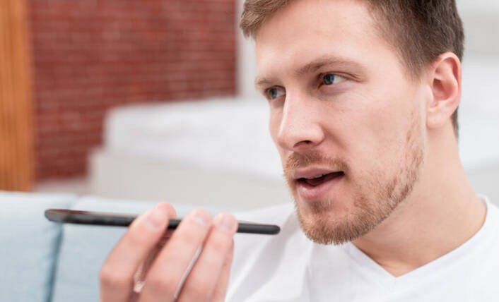 Ein Mann nutzt Siri mit seinem iPhone (Foto: Freepik) Mann spricht in sein iPhone