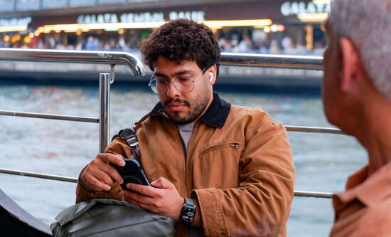 Mann mit iPhone auf einem Schiff